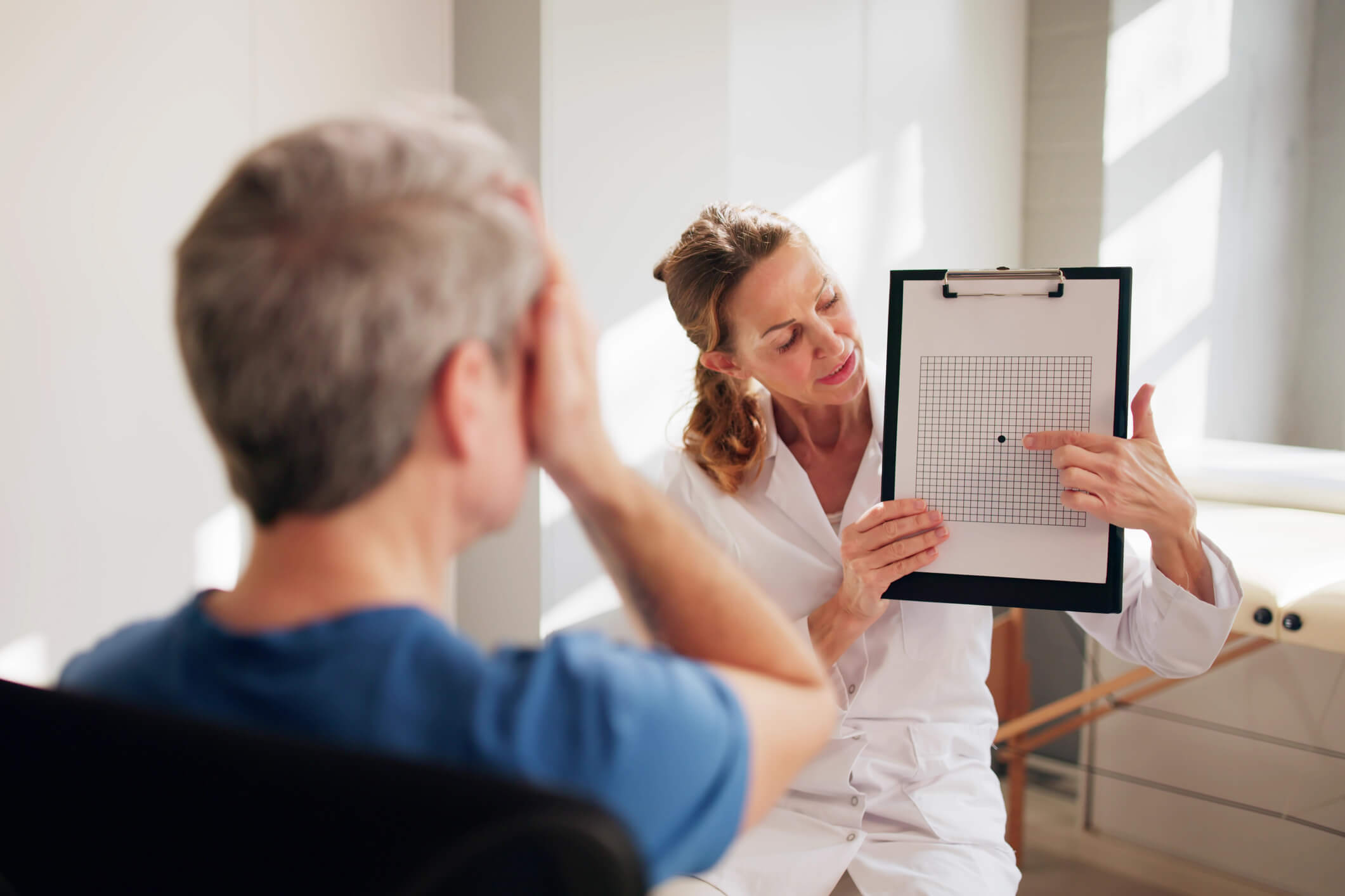 A doctor showing a visual grid test to a patient during an eye examination.